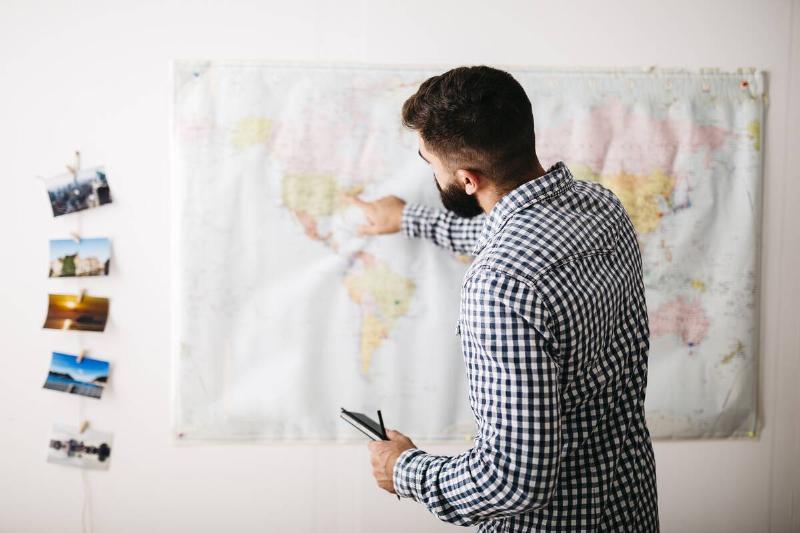 Young man selecting travel destinations on a world map.