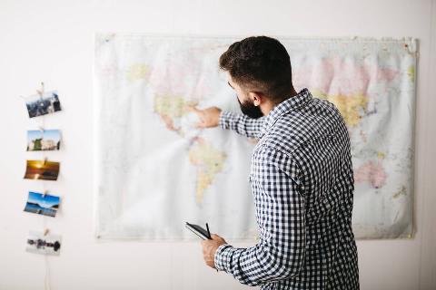 Young man selecting travel destinations on a world map.