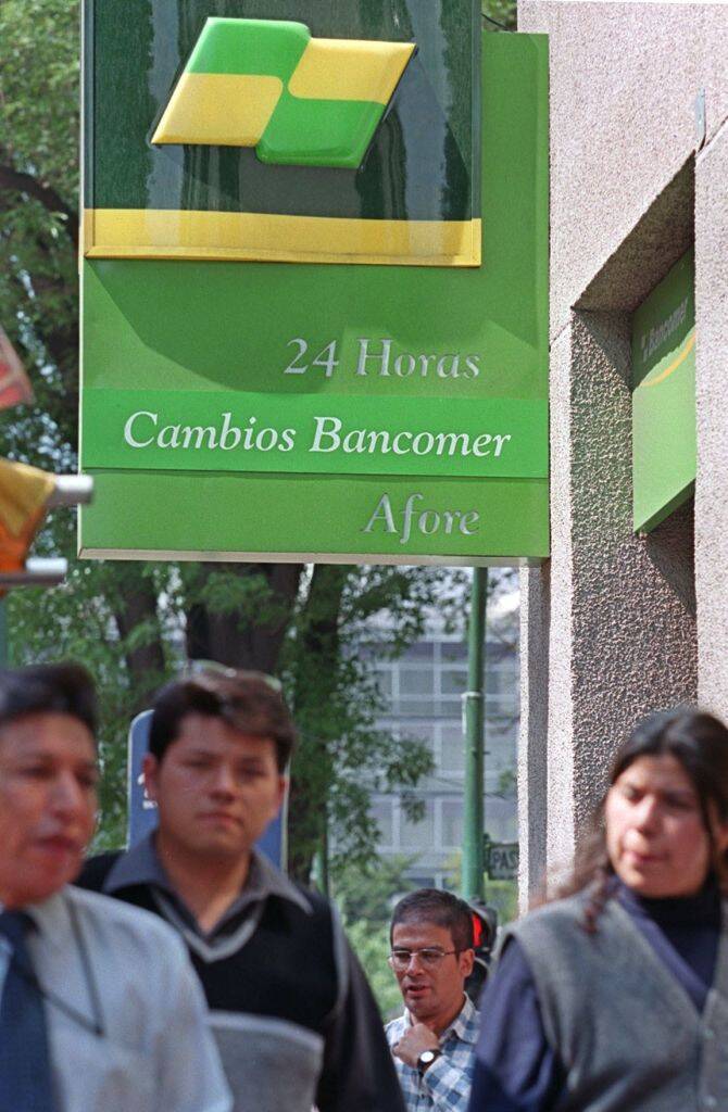 Individuals walking past a Bancomer ATM