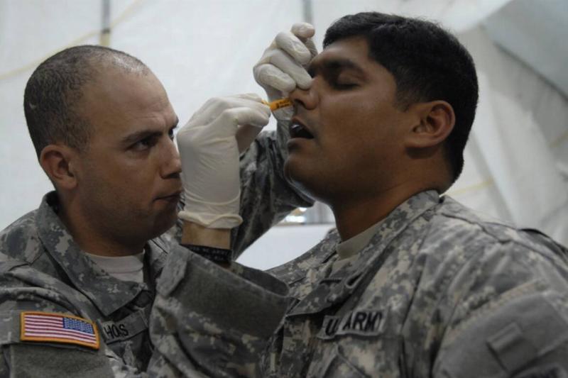 Soldier practicing putting a nasal airway in another soldier's nose.