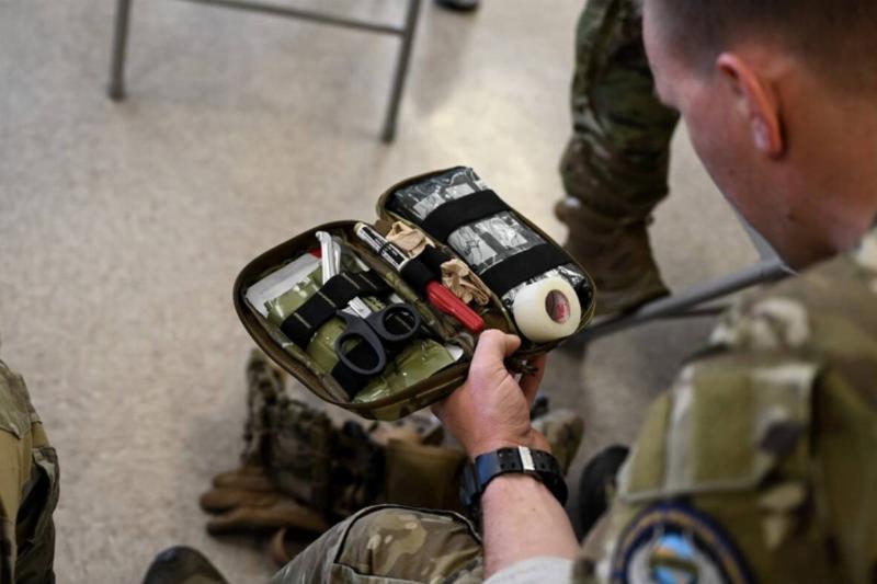 Soldier looking at open IFAK with scissors on top.