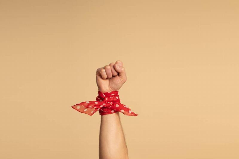 A man's hand, with a red bandana with white polka dots on his wrist.