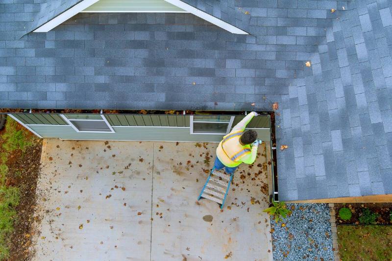 A man cleaning out a clogged gutter.