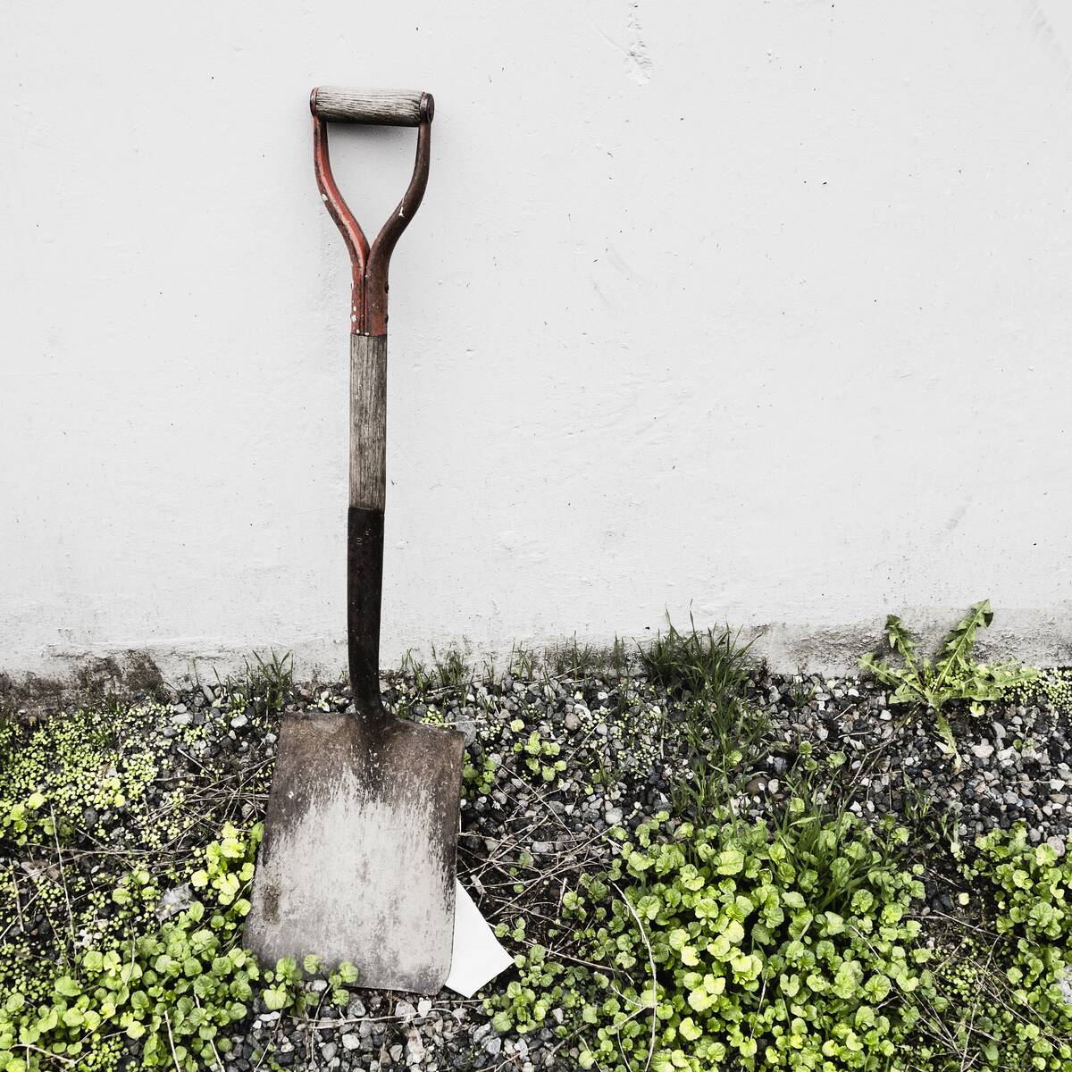 An old shovel propped against a wall.