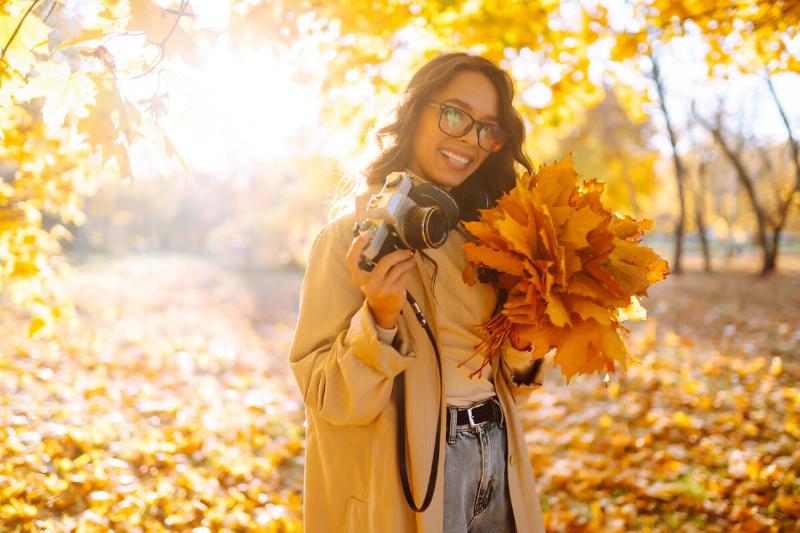 Woman holding leaves and camera.