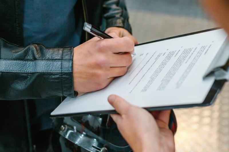 Man signing sheet on clipboard.