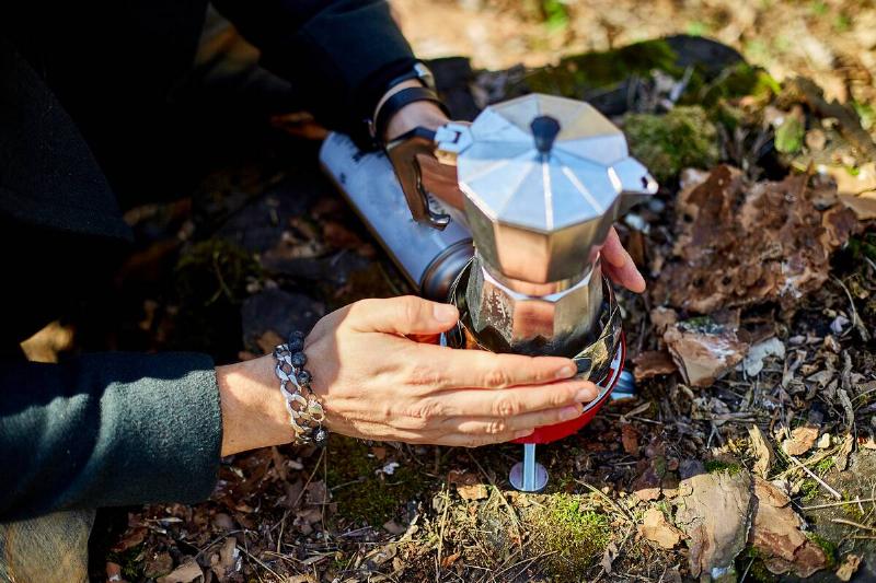 Man brewing coffee from a geyser coffee maker on a gas burner.