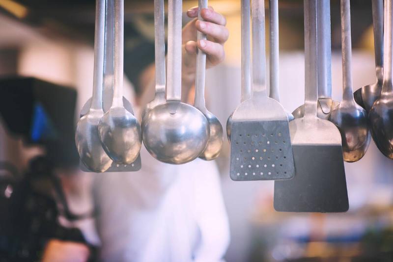 professional Cooking utensils hanging in a restaurant kitchen