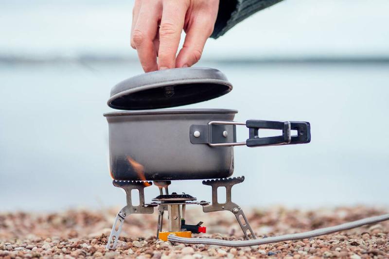 The pan with the porridge stands on the gas burner (Camping Stove). On the background of the river.