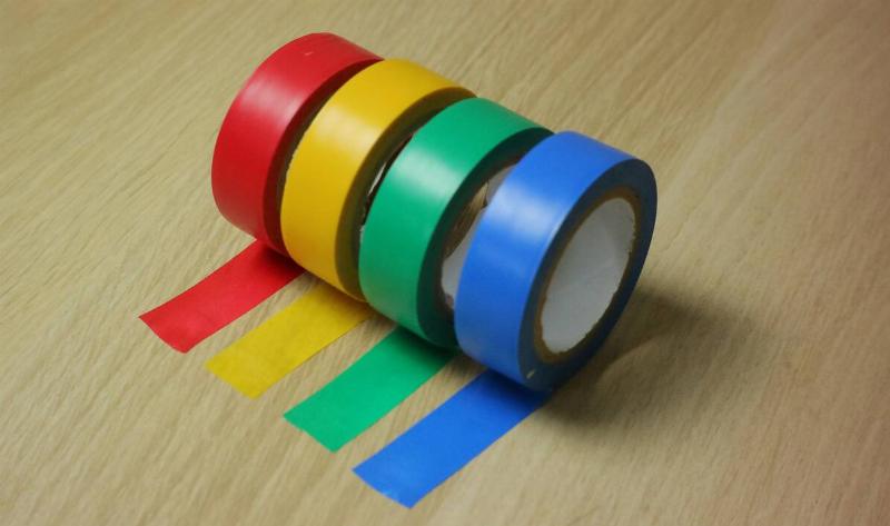 Four rolls of flagging tape, all in different colors, on a table.
