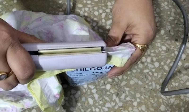 A woman using a hair straightener to reseal a plastic bag.