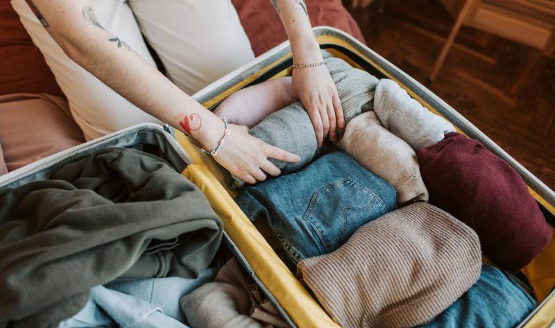 A woman rolling clothes to pack a suitcase.