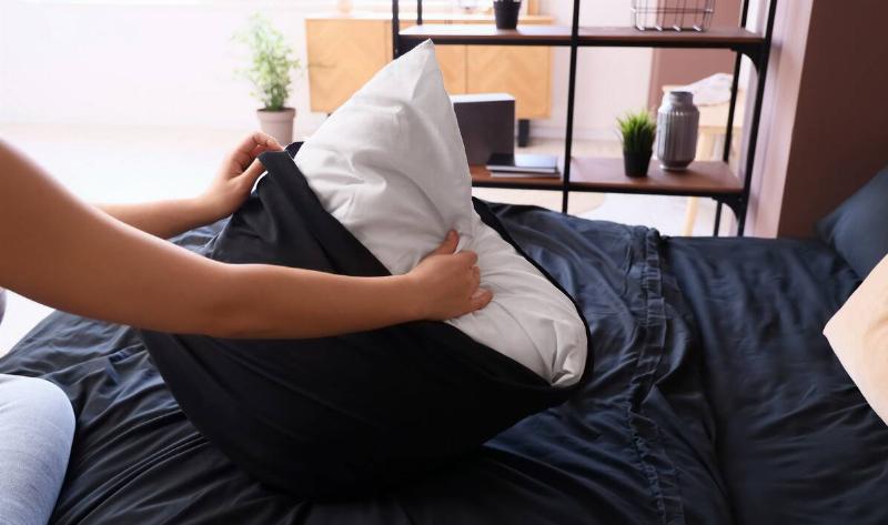 A person filling a pillowcase.