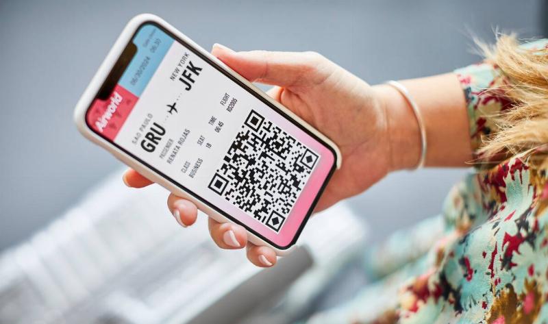 A woman holding her phone that's displaying a boarding pass.