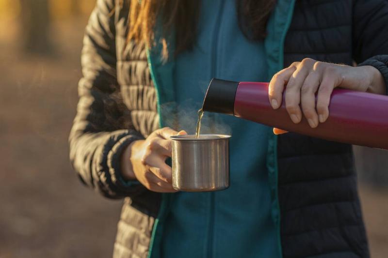Woman pouring hot liquid into mug.