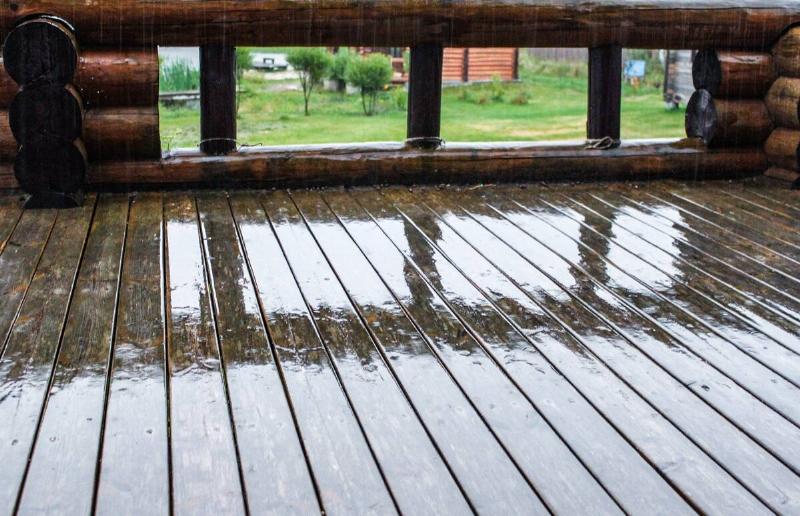 A wet wooden deck as it's raining out.