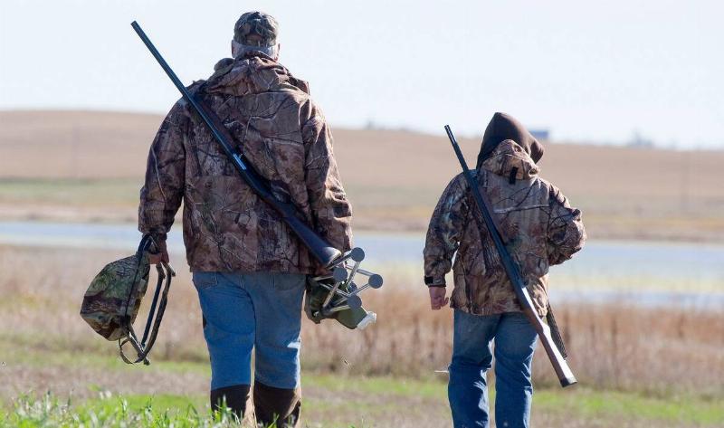 Two duck hunters walking toward to water.