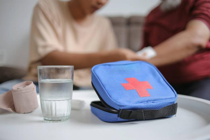 Selective Focus Of First Aid Kit With Blurry Young Man Helping Grandfather Background