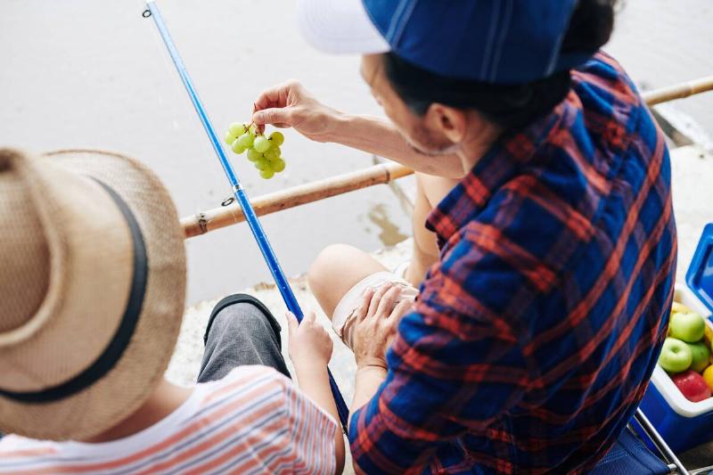 Two people eating grapes while fishing.
