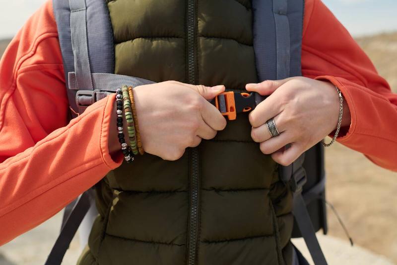 Cropped shot of unrecognizable female tourist standing outdoors adjusting chest belt on hiking backpack