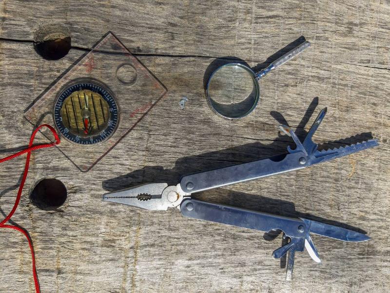 Tools for surviving in the wilderness - a compass, magnifying glass and multi-tool