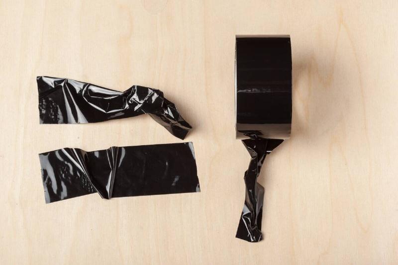 A roll of black duct tape, partially unrolled, two strips placed perpendicularly next to it.