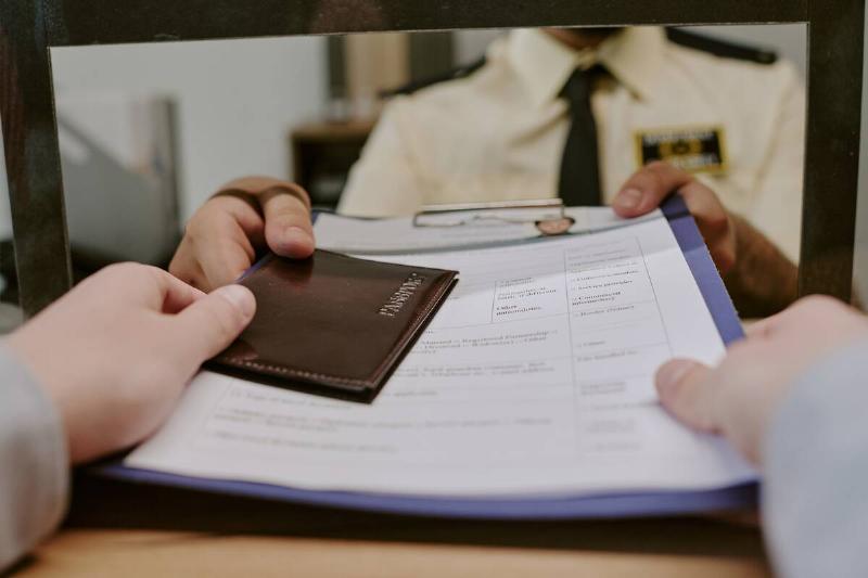 Hands handing over passport and documents at counter. 