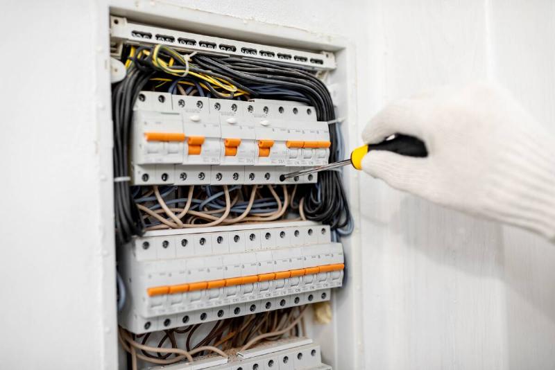 Electrician installing or repairing apartment electrical panel, close-up view