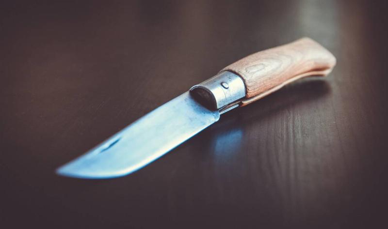 An open pocket knife on a wooden table.
