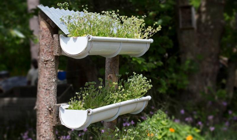 A small, handmade vertical garden with two pots made out of gutter sections.
