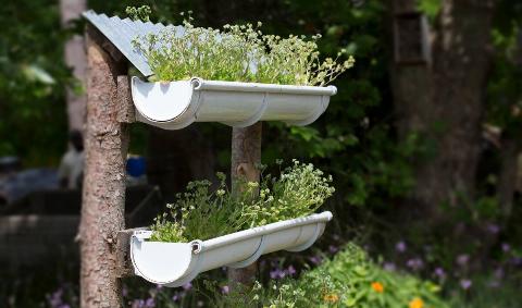 A small, handmade vertical garden with two pots made out of gutter sections.
