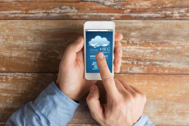 Hands holding smartphone checking the weather.