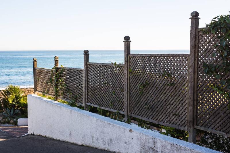 A high fence built on the corner of a road.