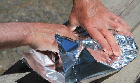 A pair of hands folding tin foil.