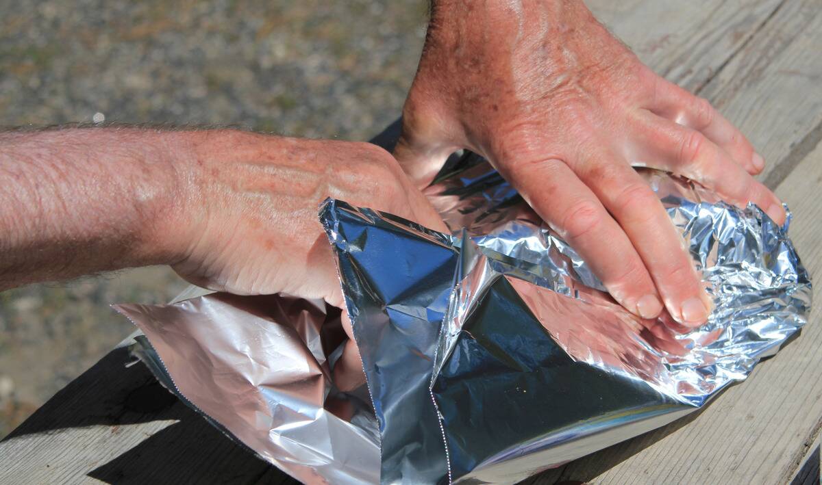 A pair of hands folding tin foil.