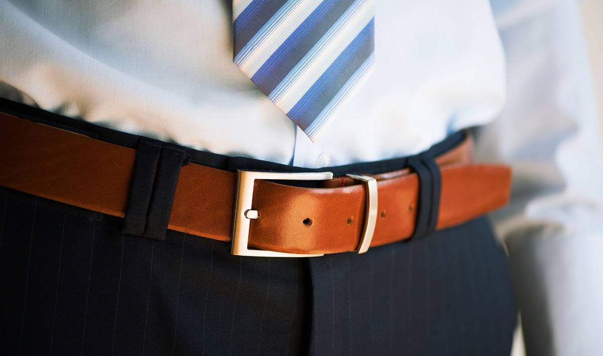 A closeup of a well-dressed man's brown leather belt.