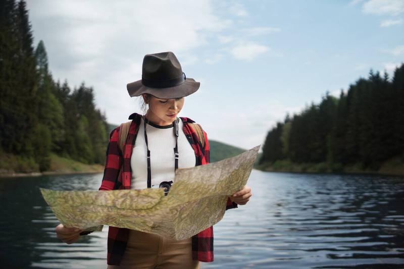 Woman standing in lake and reading map.