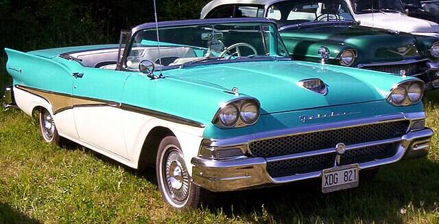 Ford Fairlane parked on grass, near a car