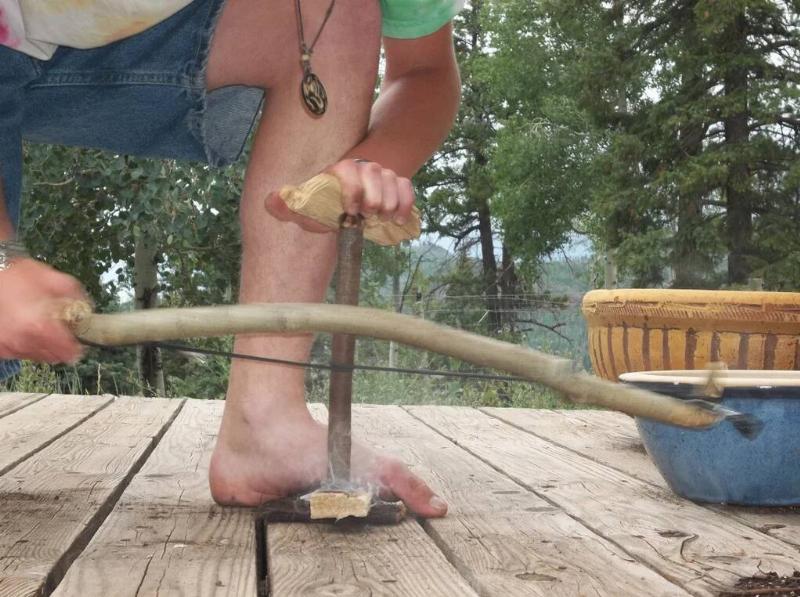 A man performing the Bow Drill method of starting a fire.