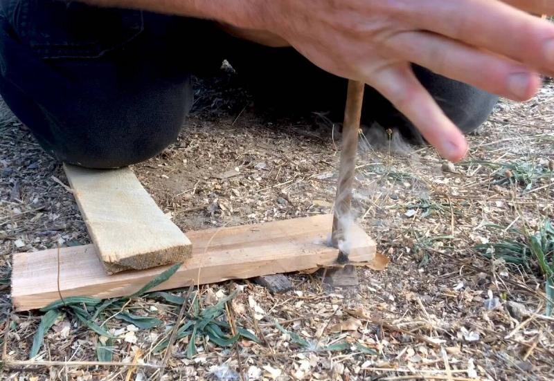 A man performing the Hand Drill method of starting a fire.
