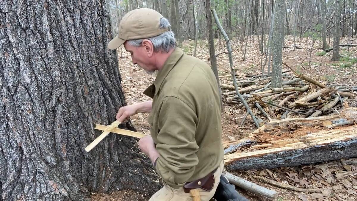 A man performing the Bamboo Fire Saw method of starting a fire.