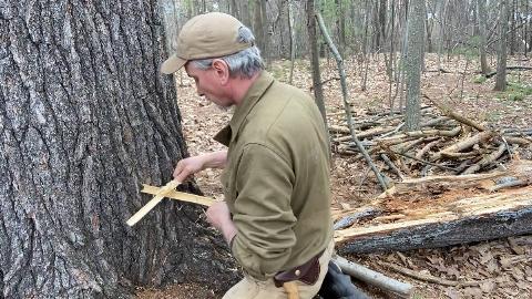 A man performing the Bamboo Fire Saw method of starting a fire.