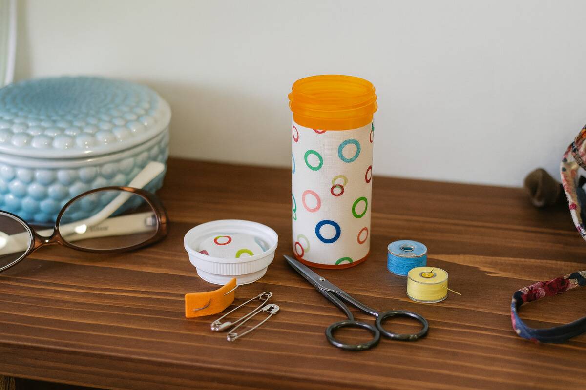 A pill bottle used to hold sewing supplies. 