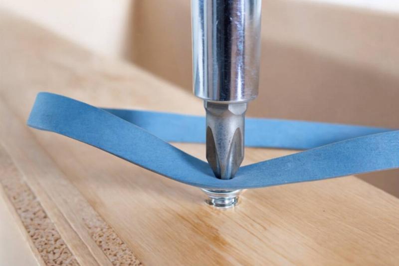 A rubber band in between a screw driver and a screw. 