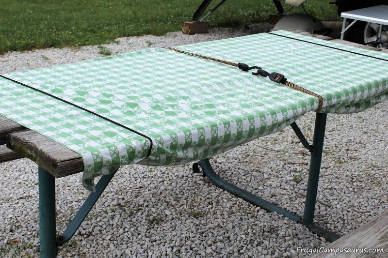 A tablecloth being held down on a table with three bungee cords.