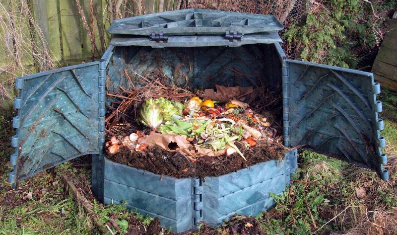A large, open, compost bin in a backyard.