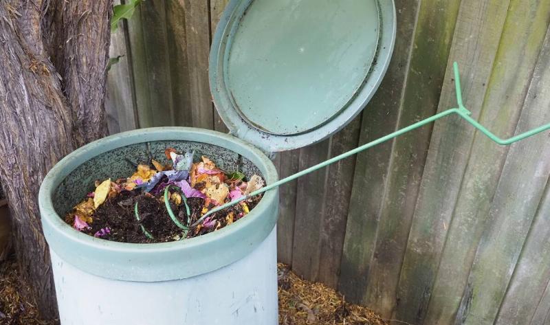 An open compost bin with a metal turner stuck in it.
