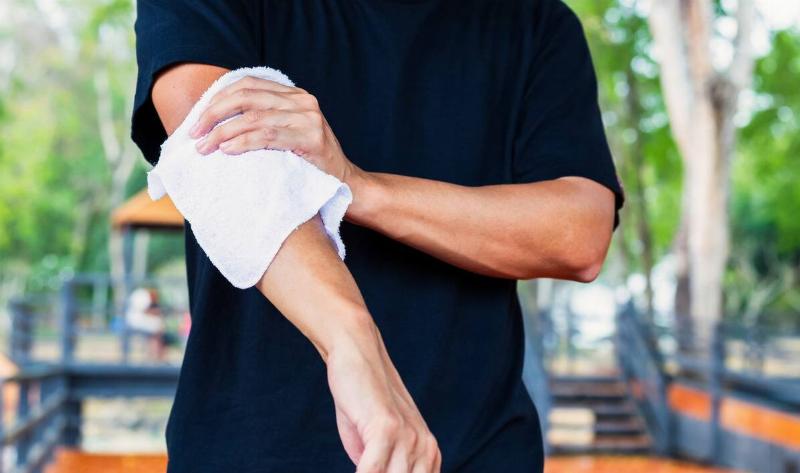 A person wiping their arm down with a clean cloth.
