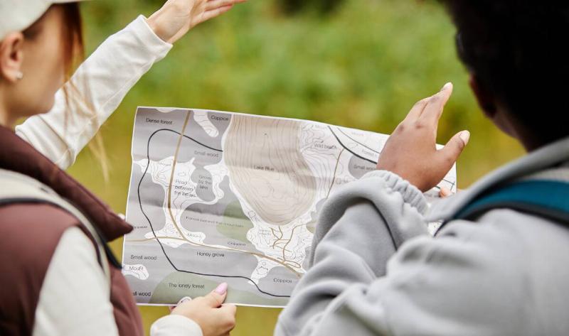 Two people looking at a paper map of the area they're in, pointing into the distance.