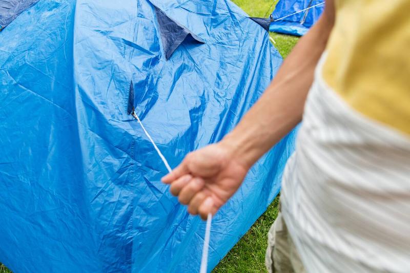 A person hanging a tarp with a piece of string.